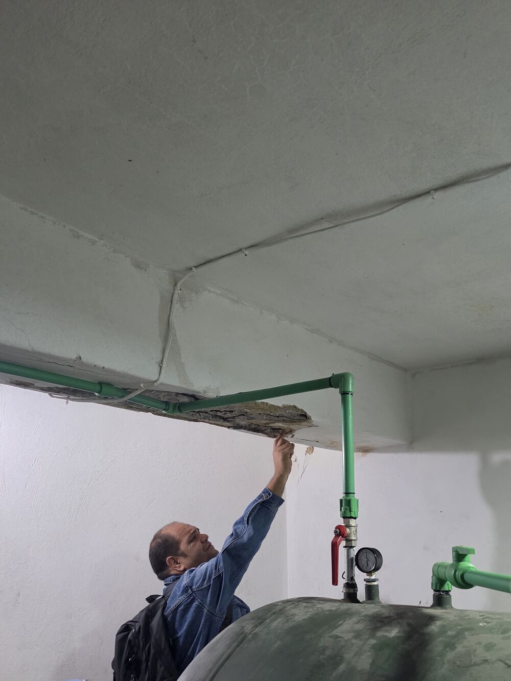 Ingeniero de Corporación 3JC señalando el desprendimiento de friso de una losa por filtración de agua durante un estudio de patología estructural